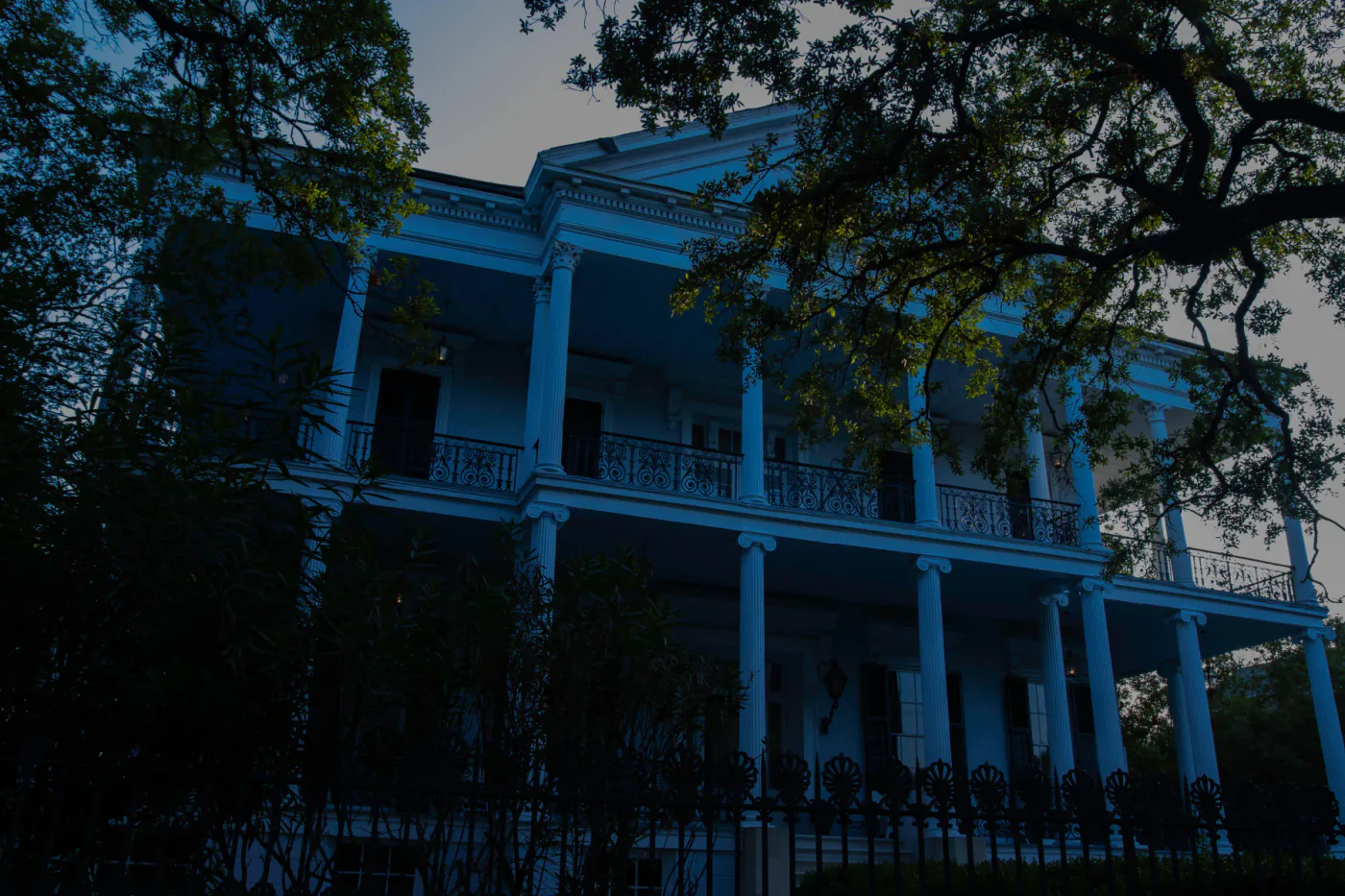 Buckner Mansion at dusk behind oak trees