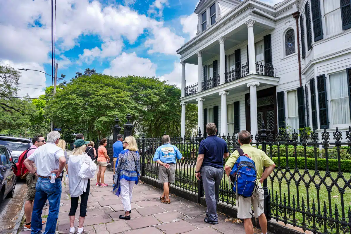 Guests walking past Buckner Mansion on a Garden District tour